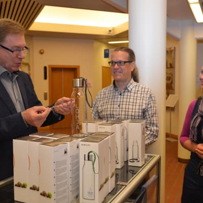 Lojos stadsdirektör Simo Juva lottar ut 20 vattenflaskor medan persontrafiklogistiker Tapio Heinonen och personaldirektör Noora Nordberg ser på.