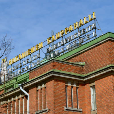 Fasaden av ett tegelrött hus med neonskylten Hagnäs saluhall