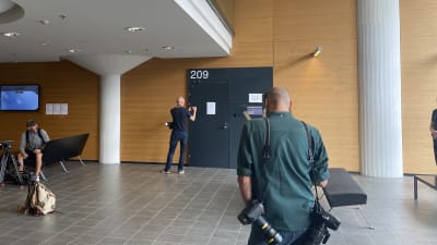 Reportrar och fotografer väntar på att dörrarna till rättssalen ska öppnas.