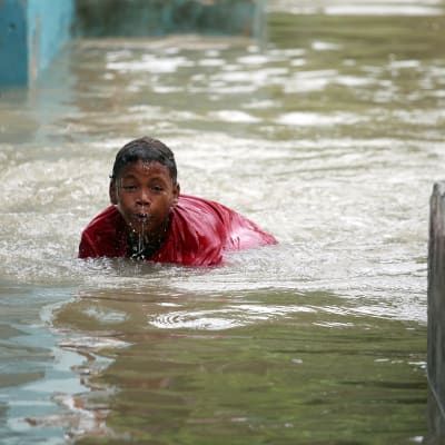 Pojke simmar i vattenmassor efter översvämningar i Santo Domingo, Dominikanska republiken 4.10.2016