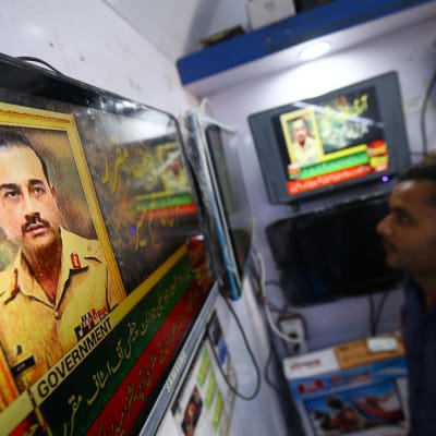 En man i Karachi ser på en tv-skärm med en bild av Pakistans nya arméchef, generallöjtnant Syed Asim Munir.