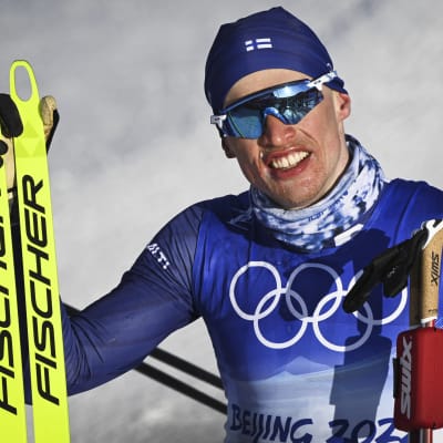 iivo Niskanen håller upp skidorna efter att han kommit i mål. 