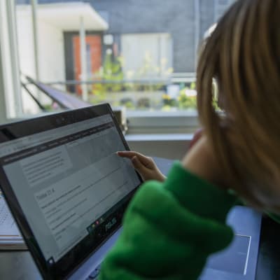 Lapsi käy etäkoulua tietokoneen avulla.