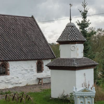 Pieni valkoinen kivikirkko ja sen vieressä valkoinen kellotapuli.