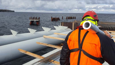 En byggarbetare bär utrustning på den plattform som utgör huvuddelen av den nya LNG-terminalen i Paldiski.
