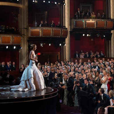 Jennifer Lawrence står på scenen och håller i sin Oscarsstatyett och ser ut över publikhavet som alla står upp och applåderar åt henne.