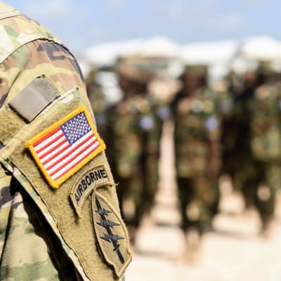 Etualalla näkyy soitlaan olkapää ja käsivarressa Yhdysvaltain lippu ja 101. maahanlaskujoukkojen tunnus. Taustalla näkyy somalialaisia sotilaita.