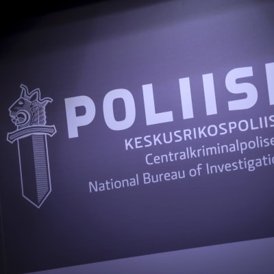 En skylt med polisens logo som föreställer ett svärd med det finska lejonhuvudet. Previd logon ses texten "Polis" och "Centralkriminalpolisen"