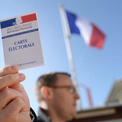 Man håller upp sitt röstningskort i kommunen Le Pin i nordvästra Frankrike den 23 april 2017-