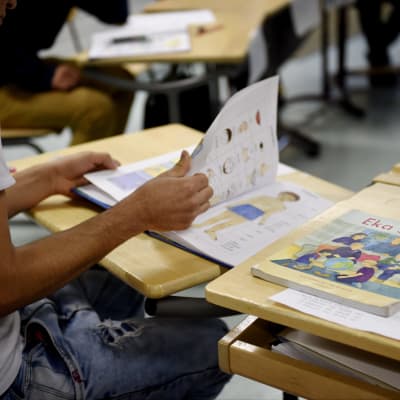 En elev bläddrar i en finsk lärobok i skolan.