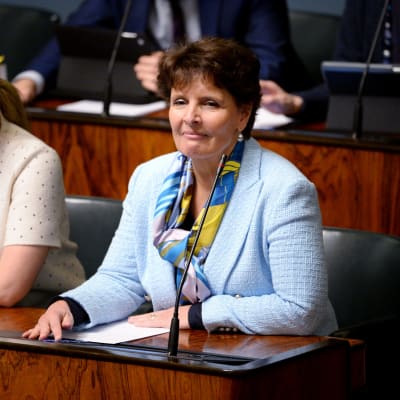 Trafikminister Anne Berner sitter i riksdagsbänken klädd i en ljusblå kavaj.