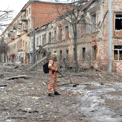 Sotilas seisoo tuhoutuneella kadulla.