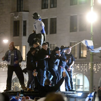 Havis Amanda iklädd landslagströja och fans som står på statyn med en flagga och firar.