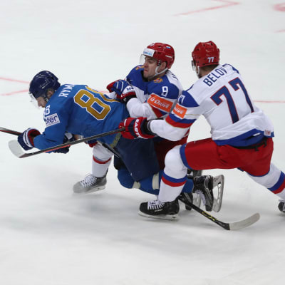 Anton Belov (R) and Viktor Antipin (C) fight for the puck with Jevgeni Rymarev (L) 
