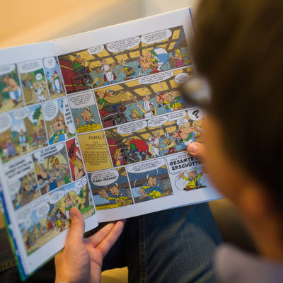 Henkilö lukee Asterix-sarjakuvaa