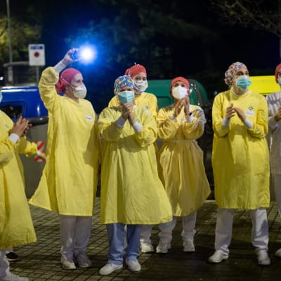 En grupp skyddsklädda sjukskötare i Barcelona vinkar åt människor som samlats på sina balkonger för att hedra dem.