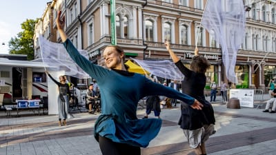 Dansare på gågatan i Åbo rör sig graciöst med vita skynken i händerna.
