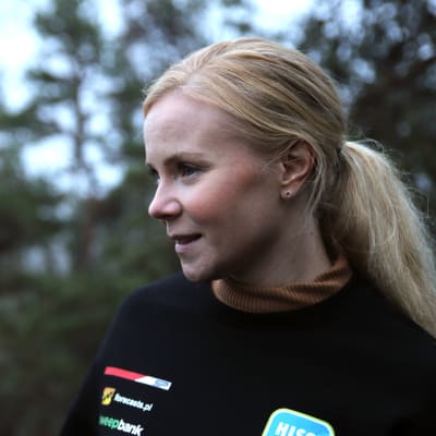 Kartanlukija Enni Mälkönen kuvan oikeassa laidassa katsoo vasemmalle kaukaisuuteen taustalla mäntyjä pienoisessa sumussa.