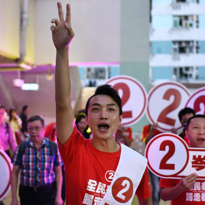 Oppositionskandidat i Hongkong firar genom att visa fredstecknet med sina fingrar.