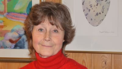 Karin Munsterhjelm, bakom har hon några tavlor.