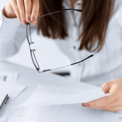 Kvinna håller i sina glasögon och ett tomt formulär.