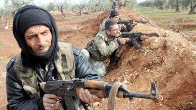 Syriska rebeller som deltar i den turkiska operationen i norra Syrien tar skydd bakom en sandhög.