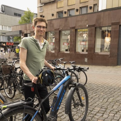 Veli-Matti Salminen seisoo sähköpyöränsä vieressä Jyväskylän keskustan pyöräparkissa.