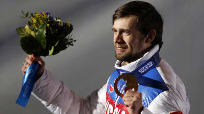 Aleksander Tretjakov håller upp sin medalj.