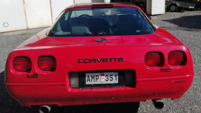 En röd Corvette-bild utanför ett garage.