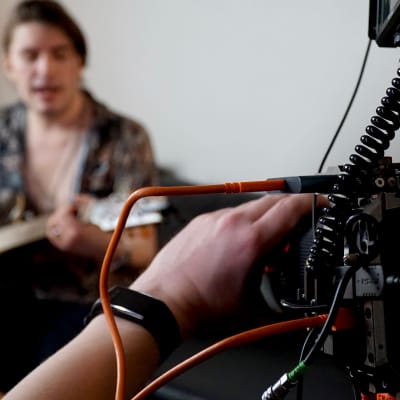 Musikern André Linman spelar gitarr och sjunger framför videokamera.