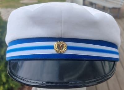 En examensmössa med blåvitt band och en gyllene kokard.