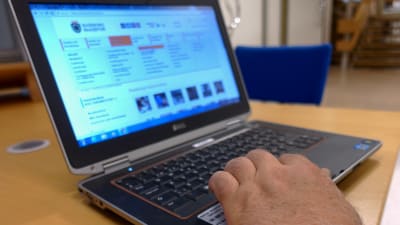 En bärbar dator med en hand på tangentbordet. På datorns skärm är Raseborgs stads hemsida öppen. 