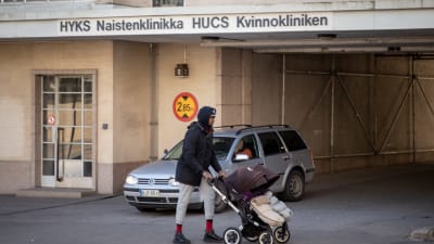 En kvinna med barnvagn utanför en byggnad. På bilden Kvinnokliniken i Helsingfors