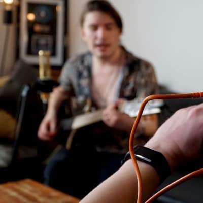 Musikern André Linman spelar gitarr och sjunger framför videokamera.