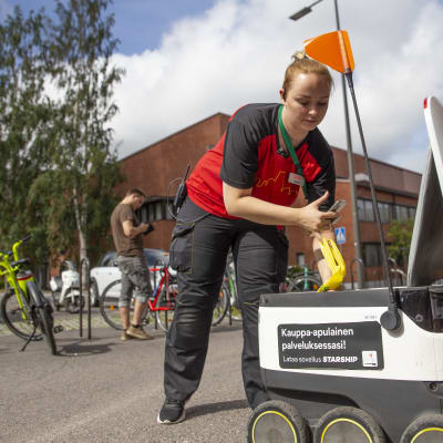 Alepan apulaismyymäläpäällikkö Jenna Suominen laittaa ostoskassia ruokarobotin sisään. 