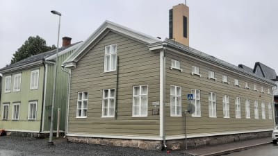 Grönt trähus vid korsning.