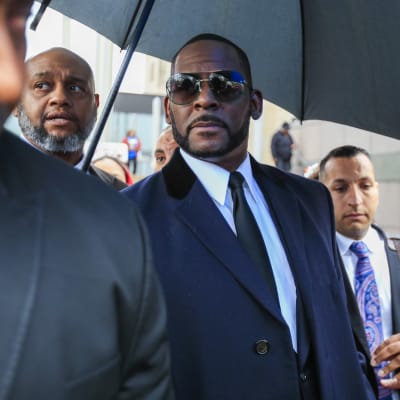 R Kelly i solglasögon och kostym utanför en domstol.