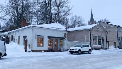 Två byggnader längs med den snöiga Alexandersgatan i Lovisa. Kyrktornet syns i bakgrunden.