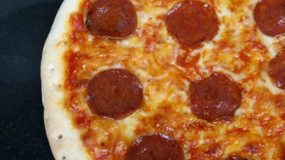 Närbild av en pizza med pepperoni.