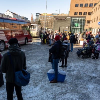 Ihmisiä Tampereen rautatieasemalla odottamassa pääsyä busseihin.