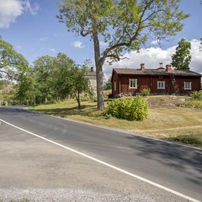 En korsnings i Fagervi, Ingå. Asfalterade vägar, en gatunamnsskylt, ett rödmålat hus, gröna träd, solsken, sommar.
