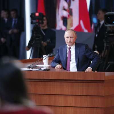 Vladimir Putin sitter bakom ett skrivbord under sin årliga presskonferens 2017. 