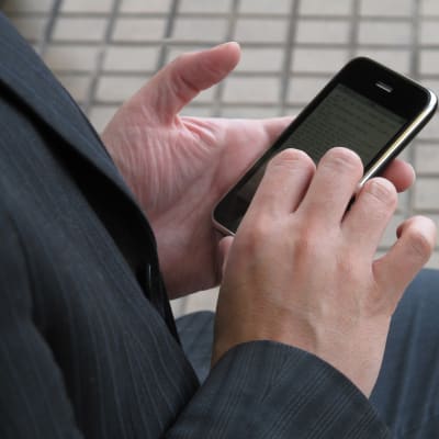 En anonym man som håller en mobil i händerna