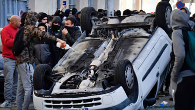 En demonstrant häller tändvätska på en bil som välts omkull i samband med lördagens demonstrationer i Marseille. 