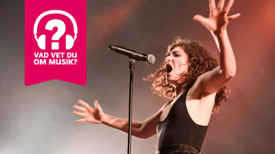 Lorde har armarna utsträckta och sjunger i en mikrofon som är i en mikrofonställning.