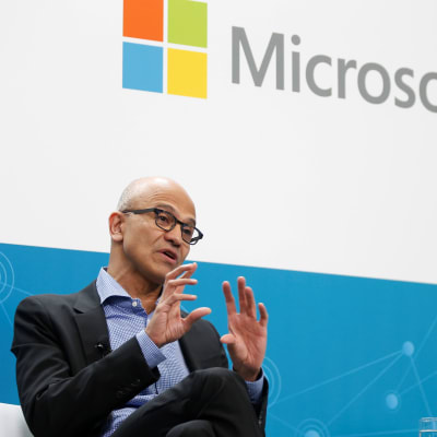 I förgrunden vd Satya Nadella, och upptill Microsofts logo.