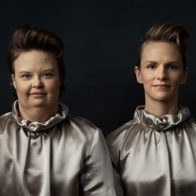 Skådespelarna Karolina Karanen och Sophia Heikkilä står i silverfärgade dräkter och ser rakt in i kameran.