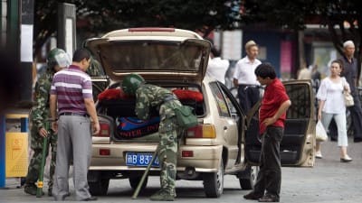 Kinesiska soldater undersöker en uigurisk mans bil