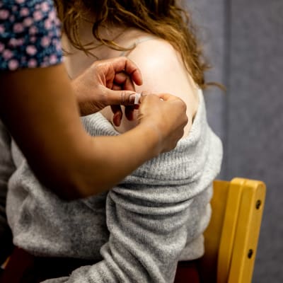 En kvinna vaccineras och får ett plåster på armen.