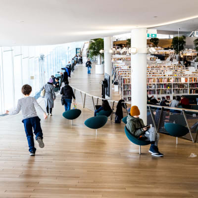 Biblioteket Odes tredje våning med fåtöljer och tiotals rader av vita bokhyllor med en massa böcker i.